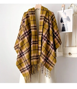 Détail d'une écharpe d'hiver à carreaux jaune et marron avec franges sur cintre en bois