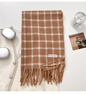 Detail of soft brown and white checkered cashmere scarf with long fringe and brand label