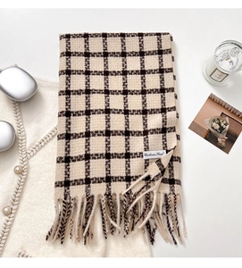 Detail of classic plaid cashmere scarf with soft tassels and woven product label