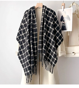 Detail of knit black and white plaid scarf with long tassels on a beige coat