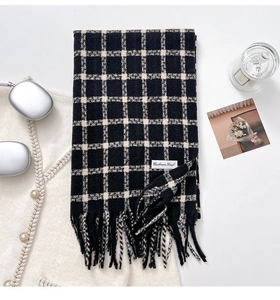 Detail of black and white checkered cashmere scarf featuring tassels and label