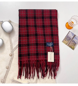 Detail of red and black plaid cashmere-like scarf with fringe and brand label on table