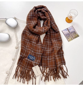 Close-up of brown plaid cashmere scarf with soft fringes and a blue brand label