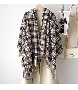 Detail of soft cashmere-feel plaid scarf with fringe tassels on a wooden hanger