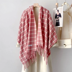 Pink and white checkered cashmere scarf with tassels and label on a white coat