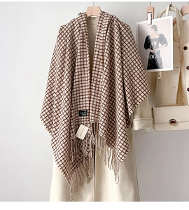 Dettaglio della sciarpa a quadri beige con morbide frange su un cappotto di lana