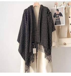 Dettaglio di scialle a quadri con frange abbinato a un cappotto beige di classe