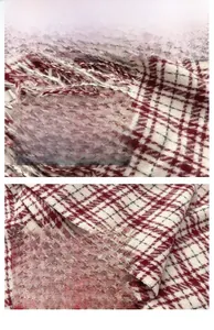 Macro shot of burgundy plaid scarf fabric texture with tassels and fine stitching