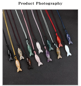 Detailed flat lay of carved gemstone fish pendants with colorful braided cord necklaces