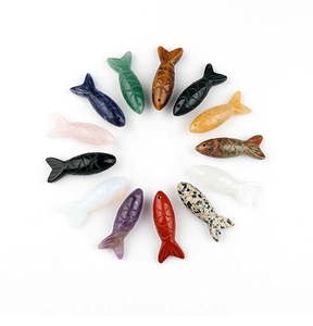 Macro view of thirteen diverse natural stone fish pendants arranged in a circular layout