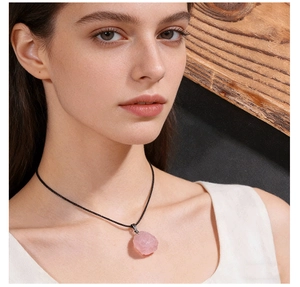 Detail of natural pink quartz raw stone pendant necklace worn by a fashion model