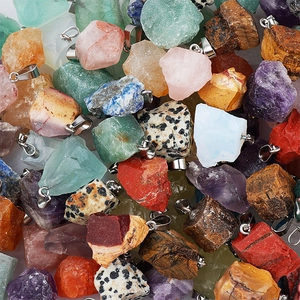 Flat lay of irregular raw natural stones with silver bails in diverse colors