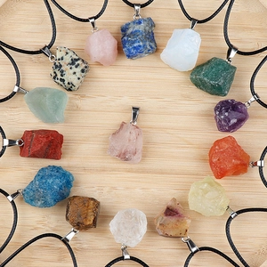 Close-up of various irregular natural crystal pendants with black wax cords on wood