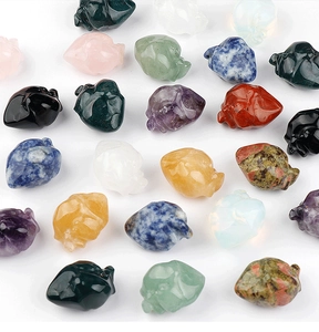 Detailed array of miniature hand-carved crystal and gemstone skulls on white background