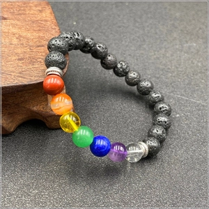 Chakra lava stone bracelet with colorful healing beads on a premium wooden base