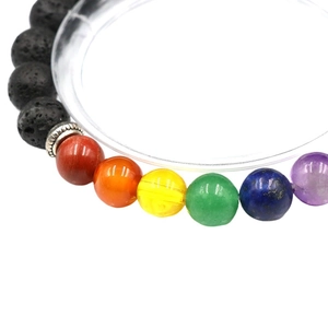 Chakra lava stone bracelet with colorful agate beads and silver charm on white background