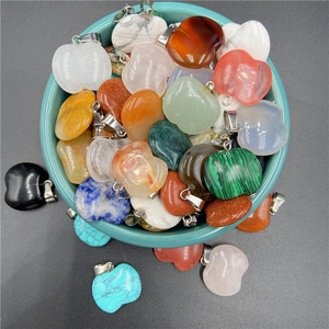 Detailed view of assorted natural stone apple pendants in a ceramic bowl for jewelry making