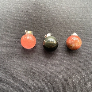 Pendentifs en cristal et agate sphériques avec fermoirs argentés sur tissu gris foncé