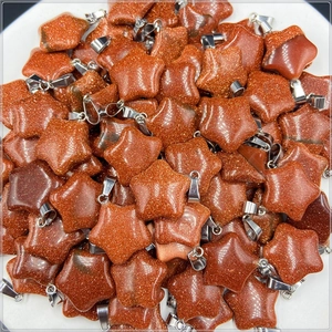 Close-up of sparkling gold sandstone star pendants with silver bails for jewelry making