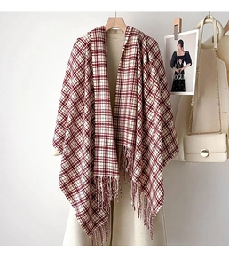 Detail of red and white plaid winter scarf with fringe, styled on a beige long coat