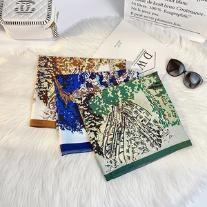 Close-up of three silk scarves with botanical prints laid on a white faux fur rug