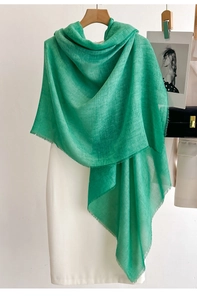 Detailed close-up of emerald green linen scarf showing soft fabric texture and frayed tassel edges