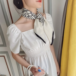 Détail d'un foulard en soie rayé noué en accessoire de cheveux sur une robe blanche