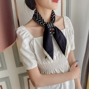 Détail d'un élégant foulard en soie noir et blanc avec motif en V chic noué autour du cou