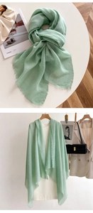 Detail showing mint green lightweight scarf with frayed edges and natural fabric texture