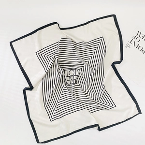Détail d'un foulard carré en mousseline rayé avec motif géométrique et lettres