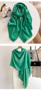Detailed view of lightweight grass green scarf with fringe edges displayed on a table