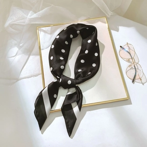 Gros plan d'un foulard en soie à pois noirs et blancs avec rayures et fini satiné
