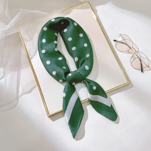Détail d'un foulard en soie vert foncé à pois et rayures sur un plateau doré
