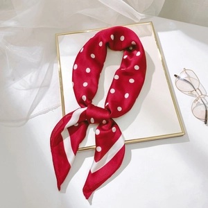 Détail d'un foulard en soie rouge à pois blancs avec des lunettes sur un tissu en résille