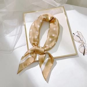 Gros plan du foulard en soie à pois dorés champagne avec un nœud élégant et doux