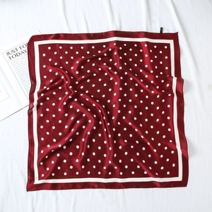 Gros plan d'un foulard en soie rouge à pois blancs avec une bordure blanche chic