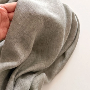 Macro detail of soft grey herringbone weave fabric texture on lightweight summer scarf