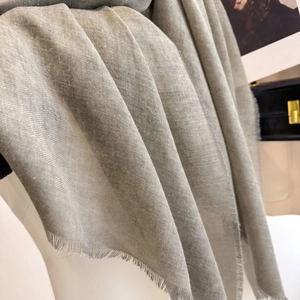 Detailed view of light grey scarf with herringbone texture and soft fringe edges
