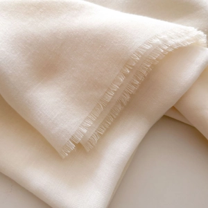 Macro shot of light beige twill fabric texture with elegant frayed tassel edge detail