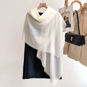 Detail of white lightweight shawl with delicate tassels and smooth texture on black dress