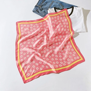 Carré de soie rose à imprimé marguerites posé à plat sur un t-shirt blanc décontracté