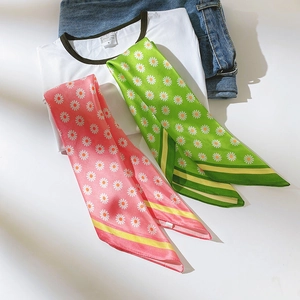 Détail de foulards en soie à imprimé marguerites rose et vert avec un t-shirt blanc