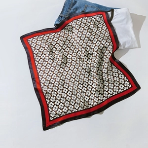 Détail à plat d'un carré de soie imprimé avec bord rouge et motifs floraux
