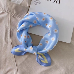 Gros plan d'un foulard en soie bleu clair avec imprimé pâquerettes noué de façon élégante