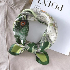 Carré de soie vert à imprimé floral drapé sur un trench-coat beige élégant