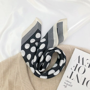 Detail of silk-like scarf with black and white polka dots and classic striped edges