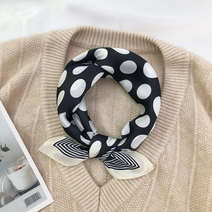 Close-up of retro black and white polka dot silk scarf with striped edges on knitwear