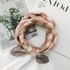 Close-up of pink and cream polka dot silk scarf with elegant knotted styling details