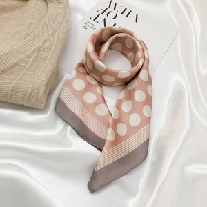 Detail of light pink silk scarf with white polka dots and striped border on satin fabric