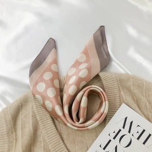 Close-up of folded polka dot silk scarf with elegant color blocking on satin fabric